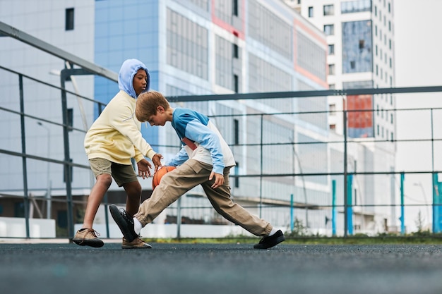 Two adolescent schoolboys playing basketball on playground