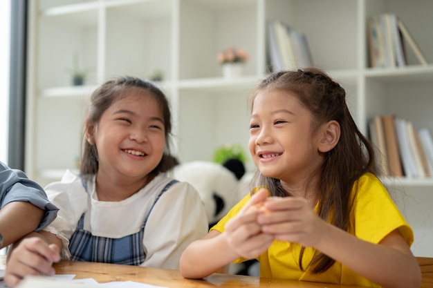 Two adorable Asian girls are enjoying talking and eating doughnuts on a snack break in a classroom