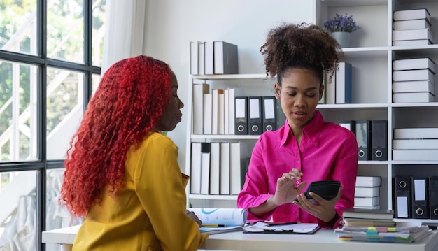 Two african american businesswomen discuss giving advice on work and plan accounting and finance