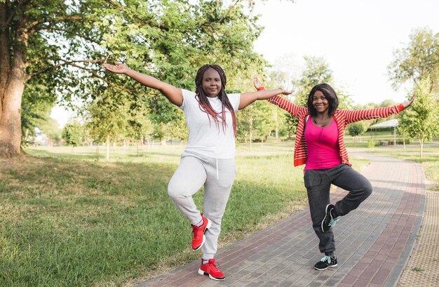 Two African-American girls are engaged in sports by performing various exercises. fitness, yoga, body care