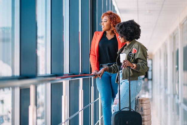 Two african girls with suitcases at the airport The concept of travel and vacation