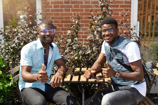 Photo two african males at a table in a summer cafe with a hand gesture