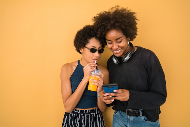 Two Afro friends using their mobile phone.