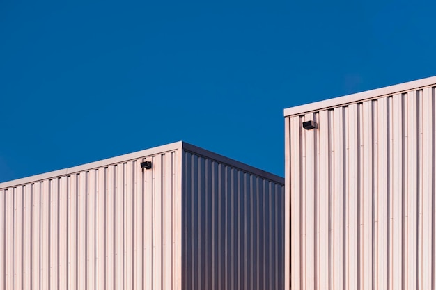 사진 푸른 맑은 하늘 배경에 대해 두 개의 알루미늄 골판지 창고 건물