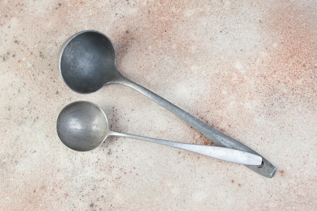 Two aluminum ladles. Vintage metal kitchen utensil on concrete background. Food photography props