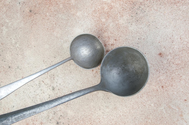 Two aluminum ladles. Vintage metal kitchen utensil on concrete background. Food photography props