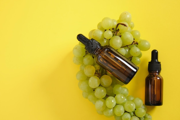 Two amber glass droppe blttle with cosmetic oil or serum and grapes