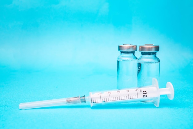 Two ampoules of vaccine with a syringe on a blue background Vaccination pictures