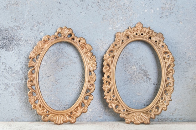 Two antique brass empty picture frames on concrete background. Photography props and copy space for text.