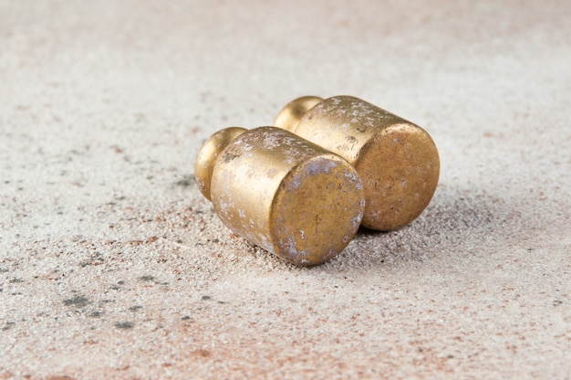 Two antique bronze weights for scales on concrete.