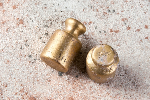 Two antique bronze weights for scales on concrete.