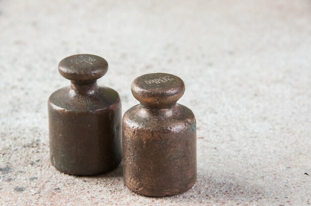 Two antique bronze weights for scales on concrete.