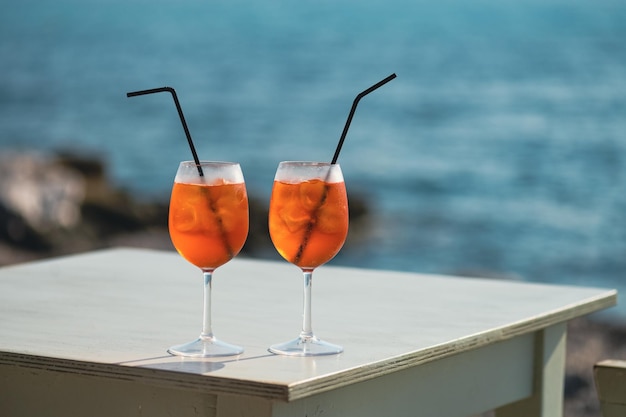 Two Aperol Spritz cocktails on the table in front of the sea background