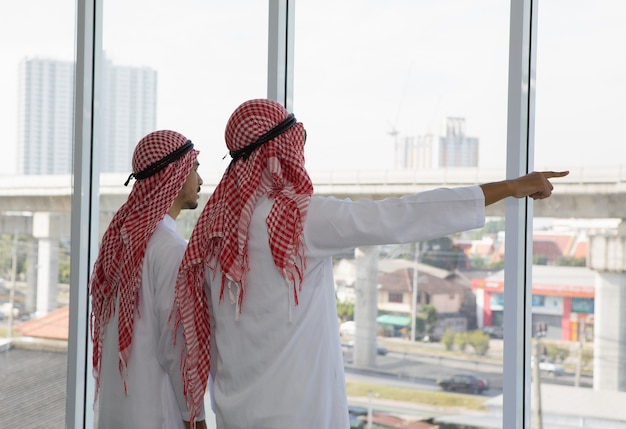 Два арабских бизнесмена, указывая на большое здание проекта