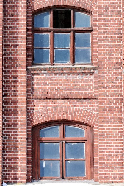 Two arched glass windows set in red brick wall