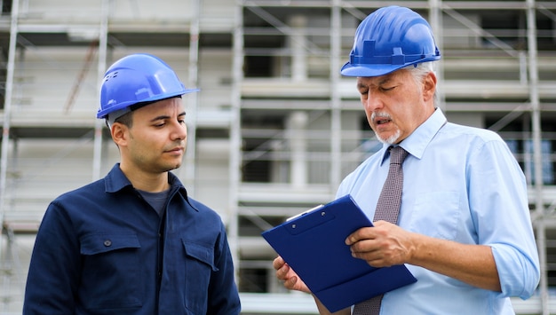 Two architect developers reviewing building plans at construction site