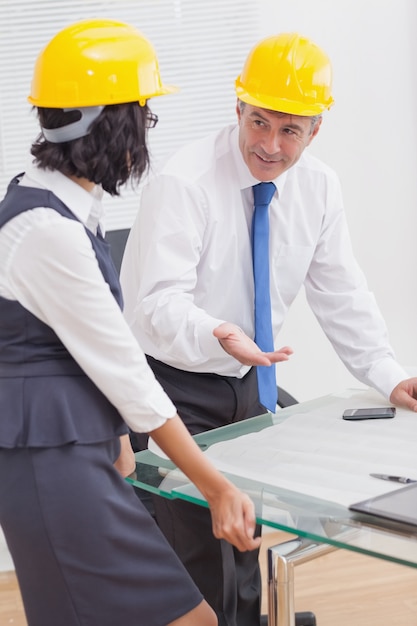 Due architetti parlando con casco giallo e sorriso