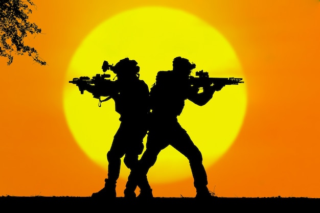 Two army soldiers silhouettes on an orange sunset background