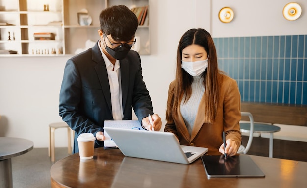 커피숍xA에 앉아 있는 사무실 책상에 있는 노트북과 함께 일하는 두 아시아 기업