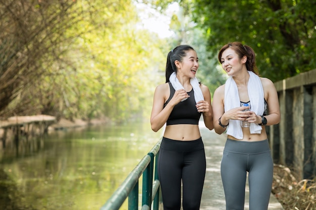 新鮮な自然の背景と一緒に朝ジョギングやランニングで屋外で2人のアジアの大人の女性
