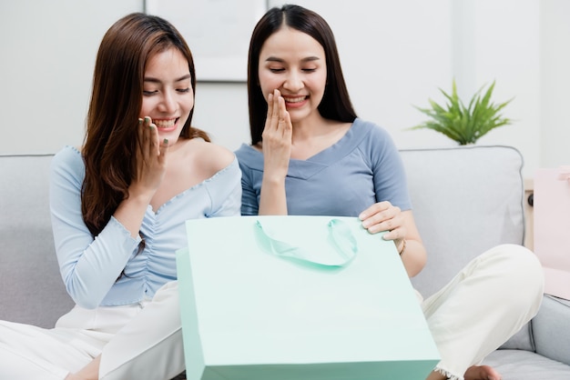 Two Asian beauty people opening the paper bag With a happy smiling face. new normal online business In the shopping experience from home