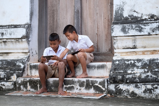 Два азиатских мальчика в школьной форме играют в игру
