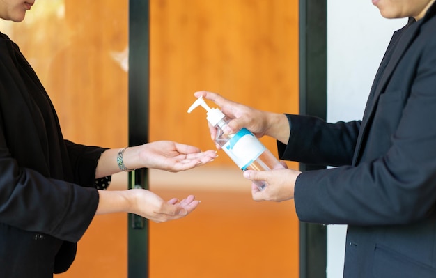 Two Asian business man and woman in black suit are washing their hands by alcohol gel