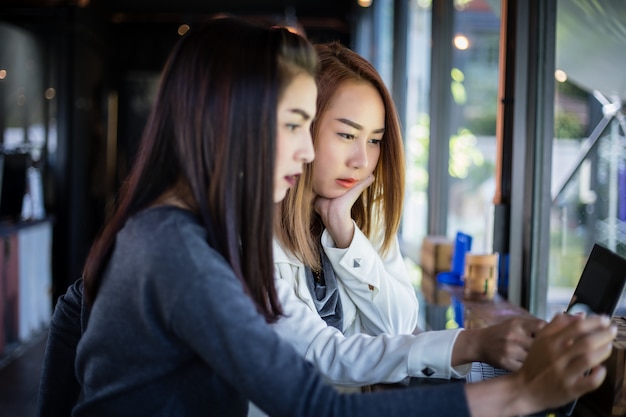 Two asian business women using notebook working and discussion of the important contract at coffee shop