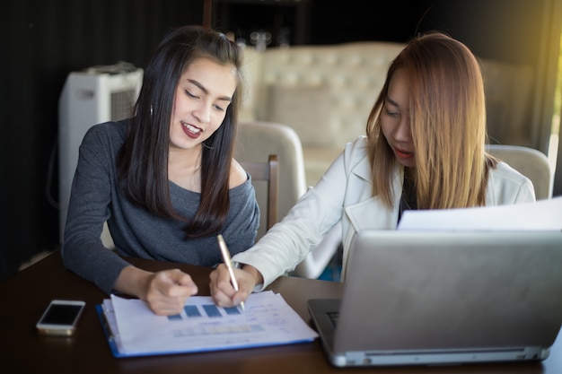 Two Asian business women using notebook working and Discussion of the important contract at office ,