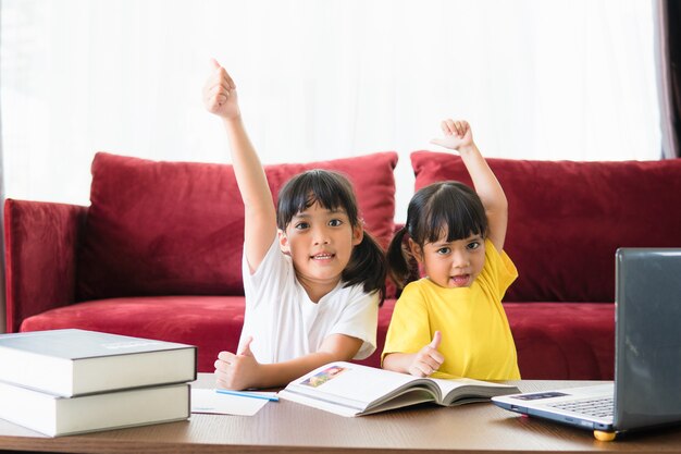 two asian child girl students study online with teacher by video call together