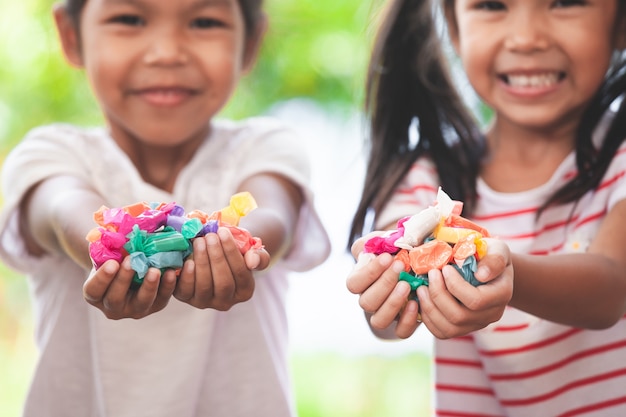 Two asian child girls holding sweet candies in thier hands
