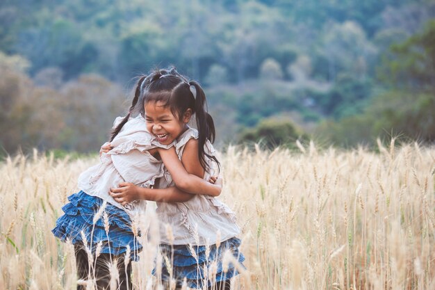 Two asian child girls hugging each other with love and playing together in the barley field