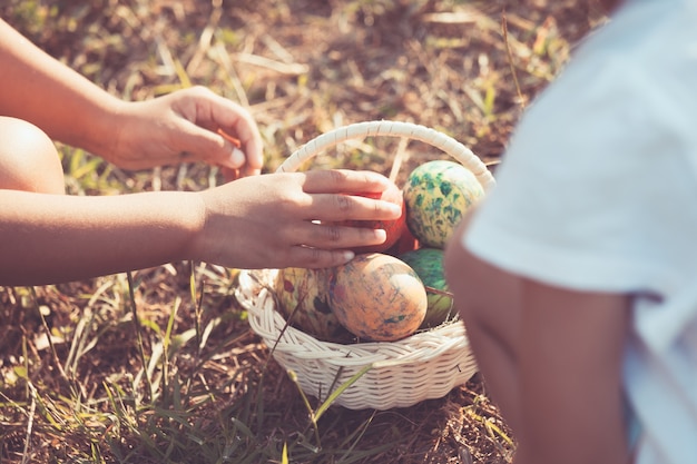 Two asian child girls playing and collecting colorful easter eggs