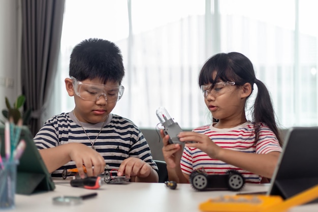 Due bambini asiatici che si divertono a imparare a programmare insieme imparando a distanza a casa stem scienza homeschooling educazione divertente distanza sociale isolamento nuovo concetto normale