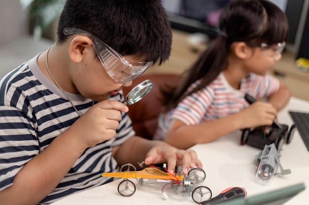 Two Asian children having fun learning coding together learning remotely at home STEM science homeschooling education fun social distancing isolation new normal concept