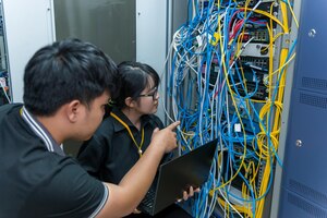 Two asian engineers working in the server roomcheck the connection problems of computer networksthailand people