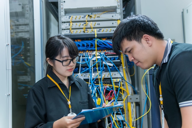 Two asian engineers working in the server roomcheck the\
connection problems of computer networksthailand people