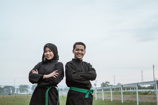 The two Asian fighters wearing pencak silat uniforms with crossed hands in nature