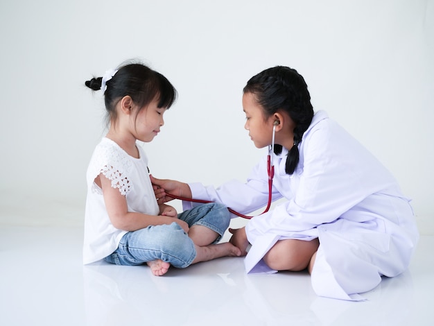 Two Asian girl playing doctor tojgether  over white background.