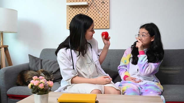 Two Asian girls playing as doctor and patient at home