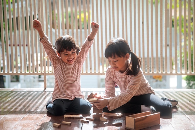 Two Asian girls playing wooden stacks at home