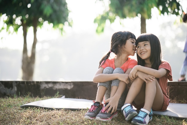 Two asian kids are taking a break in the park in the morning