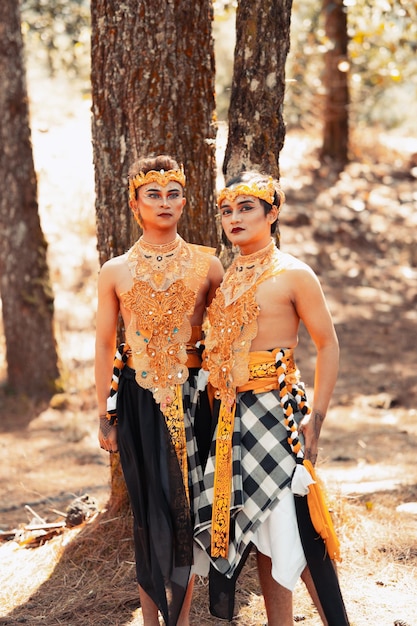 two asian men pose together with the gold crown in their hands and wearing striped clothes