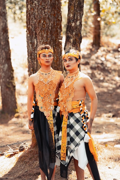 Two Asian men pose together with the gold crown in their hands and wearing striped clothes