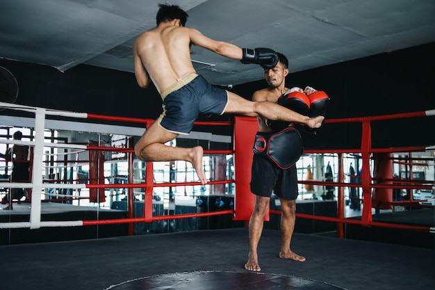 Photo two asian muay thai man practices fight together with protective equipment in boxing ring