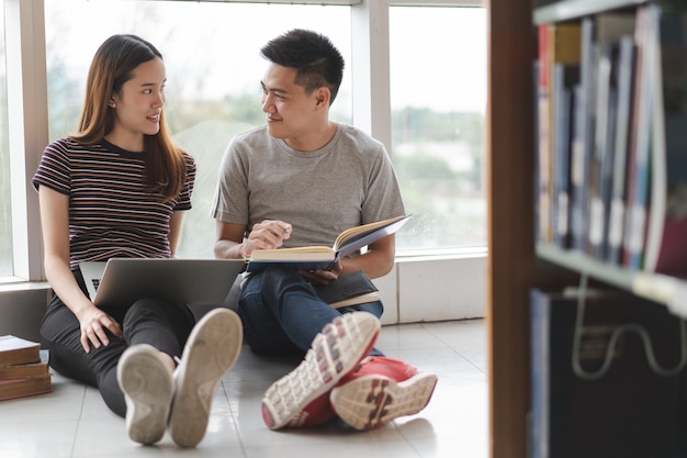 Two asian students researching for project in library.