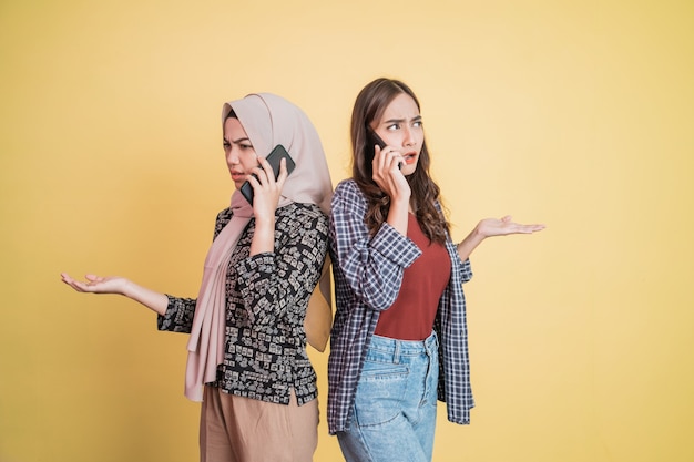 Two asian women making phone calls while standing back to back