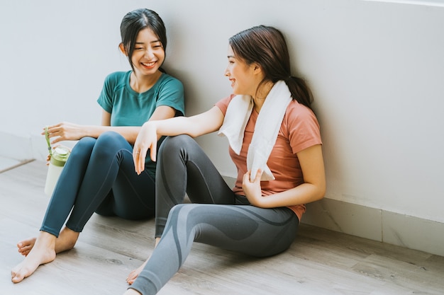 Due donne asiatiche che prendono una pausa dalla sessione di yoga