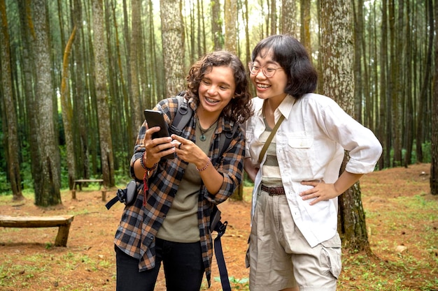 Two Asian women trekking together in the forest