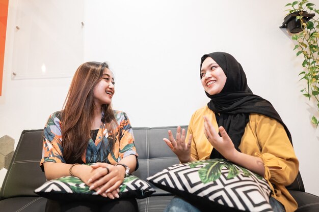 Two asian young girls chatting while sitting in a coffee shop